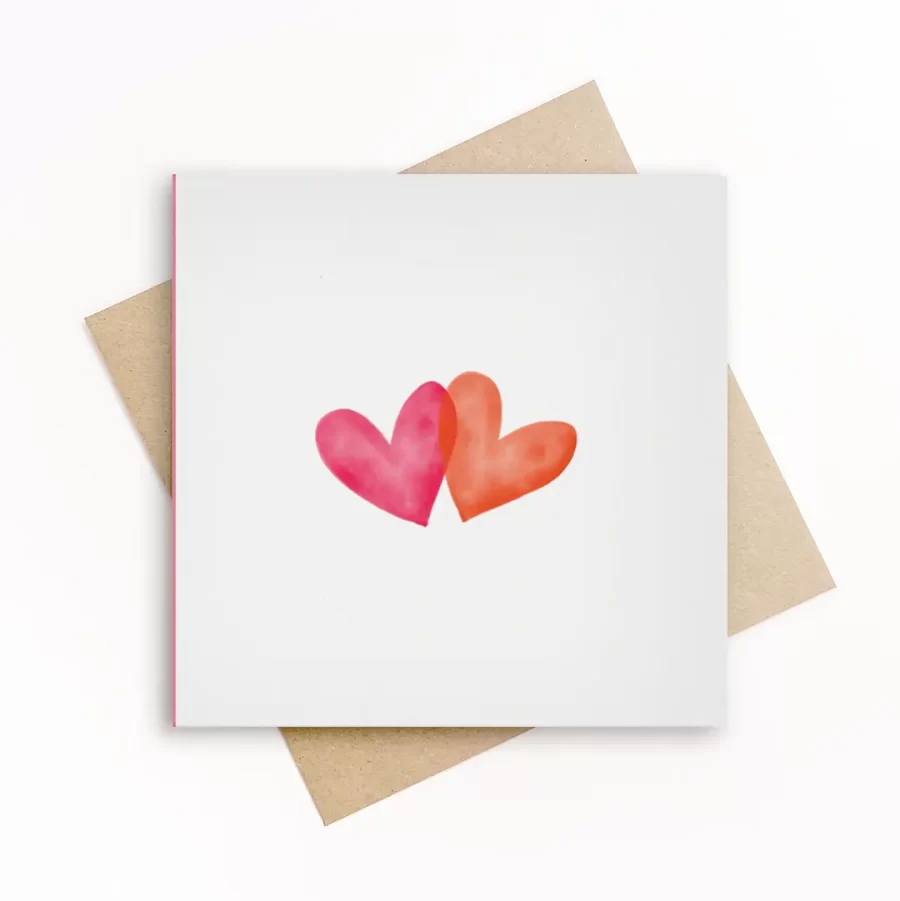 Vierkante wenskaart met twee overlappende aquarel hartjes in roze en oranje op witte achtergrond