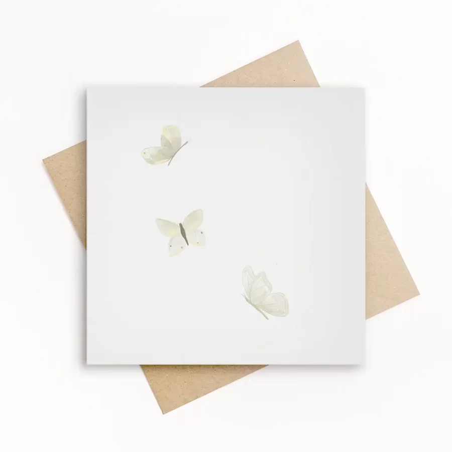 Eco-friendly wenskaart met drie zacht geïllustreerde witte vlinders op een witte achtergrond, met kraft envelop.