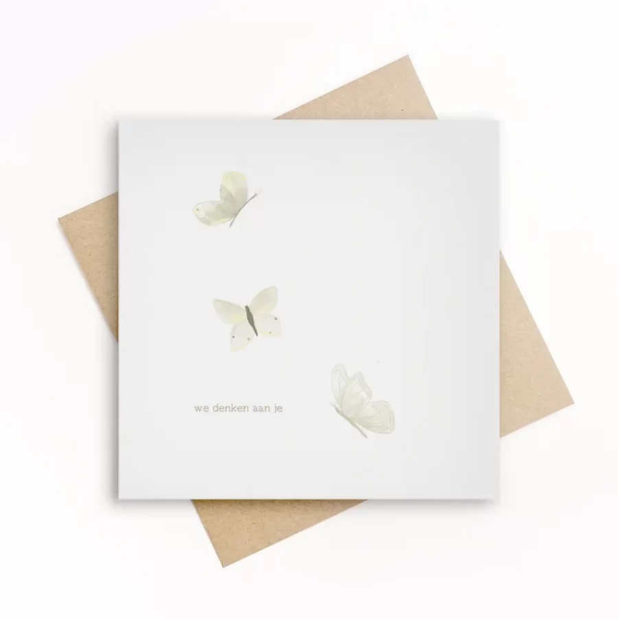Eco-friendly wenskaart met drie zacht geïllustreerde witte vlinders en de tekst we denken aan je, op wit papier met kraft envelop.